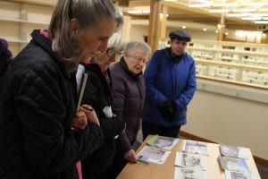 Commissioners Madeline Guhl, Jan Love, Alice Johnstone, and Jane Eidler look over photos of Sitka's last 13 libraries. (KCAW photo/Robert Woolsey)