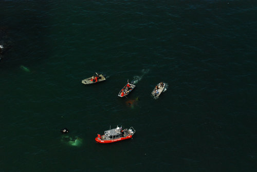 A Coast Guard 25-foot response boat crew from Station Quillayute River, Wash., along with local emergency response personnel search the water near James Island, Wash., for crew members and wreckage from a Coast Guard MH-60 Jayhawk helicopter, which crashed July 7, 2010. (USCG photo by Petty Officer Nathan Litteljohn.)