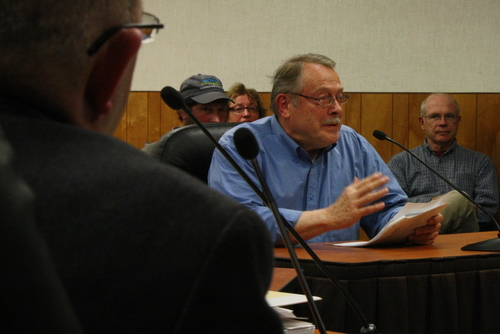 Sitka Historical Society President John Stein testifies to the Assembly as Interim City Administrator Jay Sweeney looks on in the foreground. Stein is hoping the Assembly will restore a $20,000 cut in the city's contribution to his group. (KCAW photo by Ed Ronco)