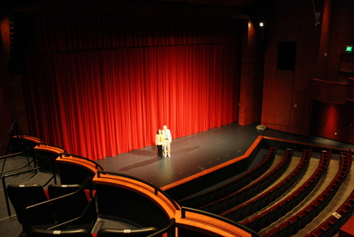 Sergio Fisher and his wife, Fay, stand on the stage at the Performing Arts Center in Sitka. Fisher was the architect who designed the interior of the theater. It was his first time back to Sitka since the building opened in 2007. (KCAW photo by Ed Ronco)
