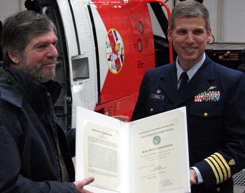 John Hagen (l.) receives his commendation from Air Station SItka commander Cpt. Ward Sandlin. (KCAW photo/Robert Woolsey)