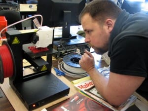 Metlakatla Science teacher Jason Pipkin watches as the printer creates metric screws for a quadcopter his students are building. (KCAW photo/Robert Woolsey)