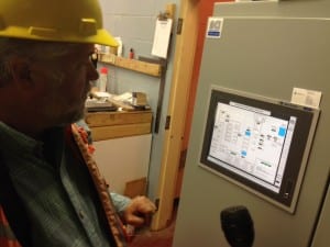 Buggins looks over the PLC display (Programmable Logic Controller). It's a computer, and Sitka has purchased it, along with several of the pumps and valves in the temporary system. (KCAW photo/Robert Woolsey)
