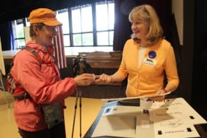 Poll worker Kim Hunter helps voters submit their ballot for counting -- and gives out stickers -- on primary day. (KCAW photo/Rachel Waldholz)