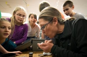 Gwen Baluss of the U.S. Forest Service blows on a junco to reveal fat deposits, in Patty Dick's 6th grade class at Blatchley Middle School. (Photo by Bethany Goodrich, Sitka Conservation Society)