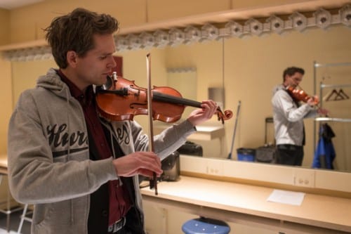 Violinist Mads Tolling warms up in the dressing room. (Emily Kwong/KCAW photo)