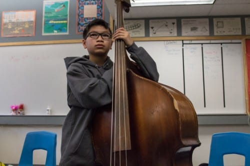 A young performer looks on as Active Duty Airwoman Emily Wheaton puts a bass line on the board. (Emily Kwong/KCAW photo)
