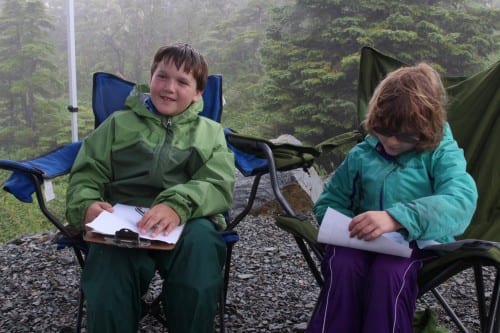 Tracking it: Logan Kluting, 10, and Jasmine Wolfe, 8, listen to the radio while logging which runners had passed each check point. (Rachel Waldholz/KCAW)