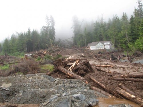A new home under construction on Sitka's Kramer Avenue was totally obliterated in the slide. A neighboring new home stands unscathed. Four people remain missing . (NOAA/NWS photo, Joel Curtis)