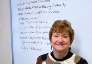 Southeast Senior Services Director Marianne Mills poses with a partial list of other organizations it works with. (Photo by Ed Schoenfeld/CoastAlaska News)