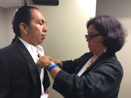 Dorothy Grant straightens the jeweled buttons on the Eagle/Raven tuxedo, modeled by Conrad Frank. Grant designed the piece for First Nations actor Duane Howard to wear to the 2015 Oscars. (Emily Kwong/KCAW photo)