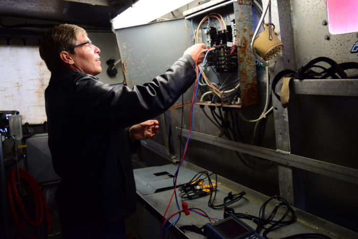 Mike Gaffney connects the power quality analyzer to the fishing vessel's electric panel. (Photo courtesy of Sustainable Southeast Partnership/Bethany Goodrich.)