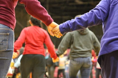 A student and elder take hands during a group dance at Mt. Edgecumbe. (Emily Russell/KCAW)