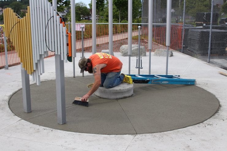 Brandon White smooths concrete in the musical instrument structure.