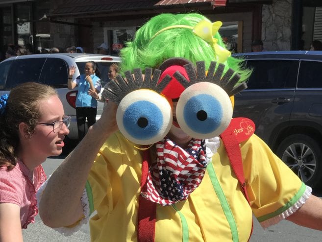 A clown displays her binoculars.
