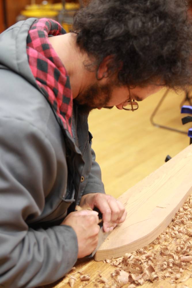 Pacific High School senior Daniel Abril focuses his efforts on the tip of a paddle he's been carving at the Sitka National Historical Park's visitor center for weeks. 