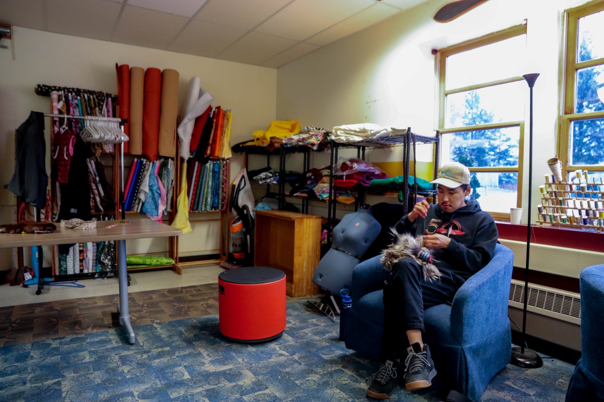 Visiting artist Golga Oscar sits in MEHS' culture room sewing a nusqurrun (KCAW/Cotter)